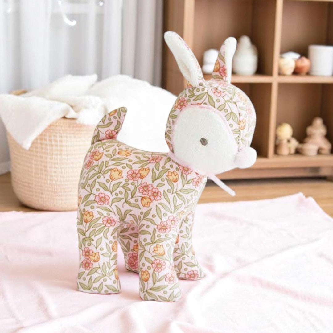 A soft pink floral baby deer rattle toy with stitched details, photographed on a neutral background.