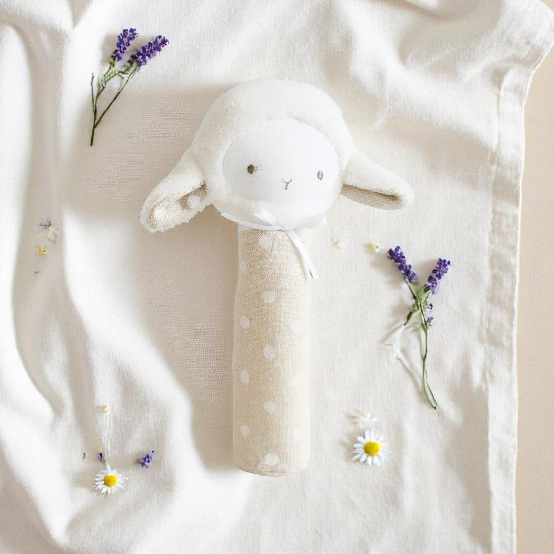 A soft lamb-shaped squeaker toy in white linen with a subtle spot print and stitched features, photographed on a pale neutral background.