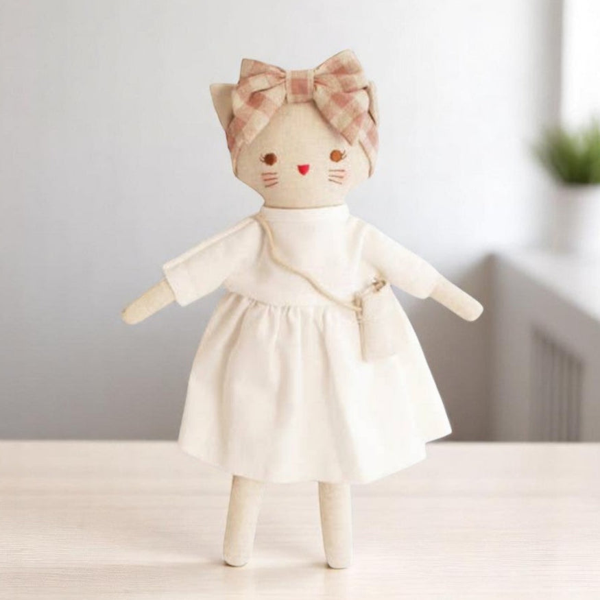 A soft plush cat named Lilly Kitty wearing a white linen dress, sitting sweetly against a neutral background.