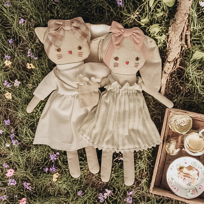 A soft plush cat named Lilly Kitty wearing a white linen dress, sitting sweetly against a neutral background.