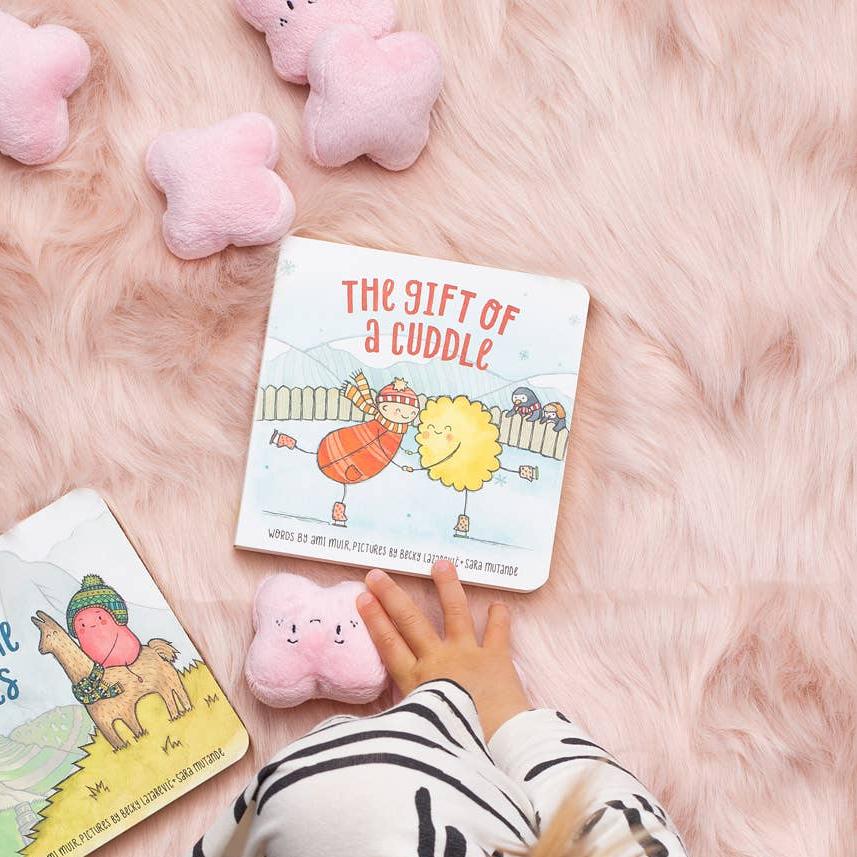 A board book edition of The Gift of a Cuddle, with a gentle cover illustration of a parent and child sharing a cuddle beneath stars.