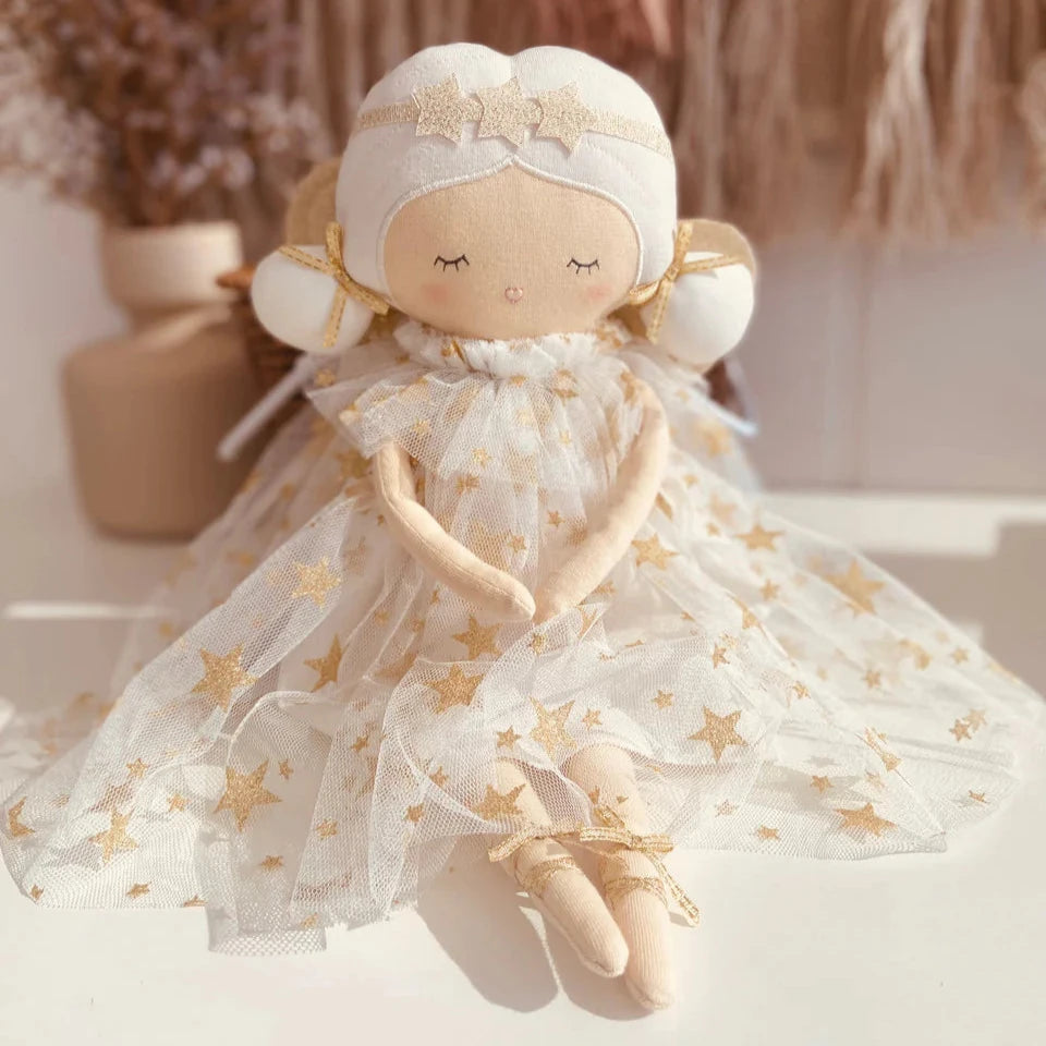 A tall fabric fairy doll in an ivory dress with gold shoes and tulle wings, resting softly against a neutral background.